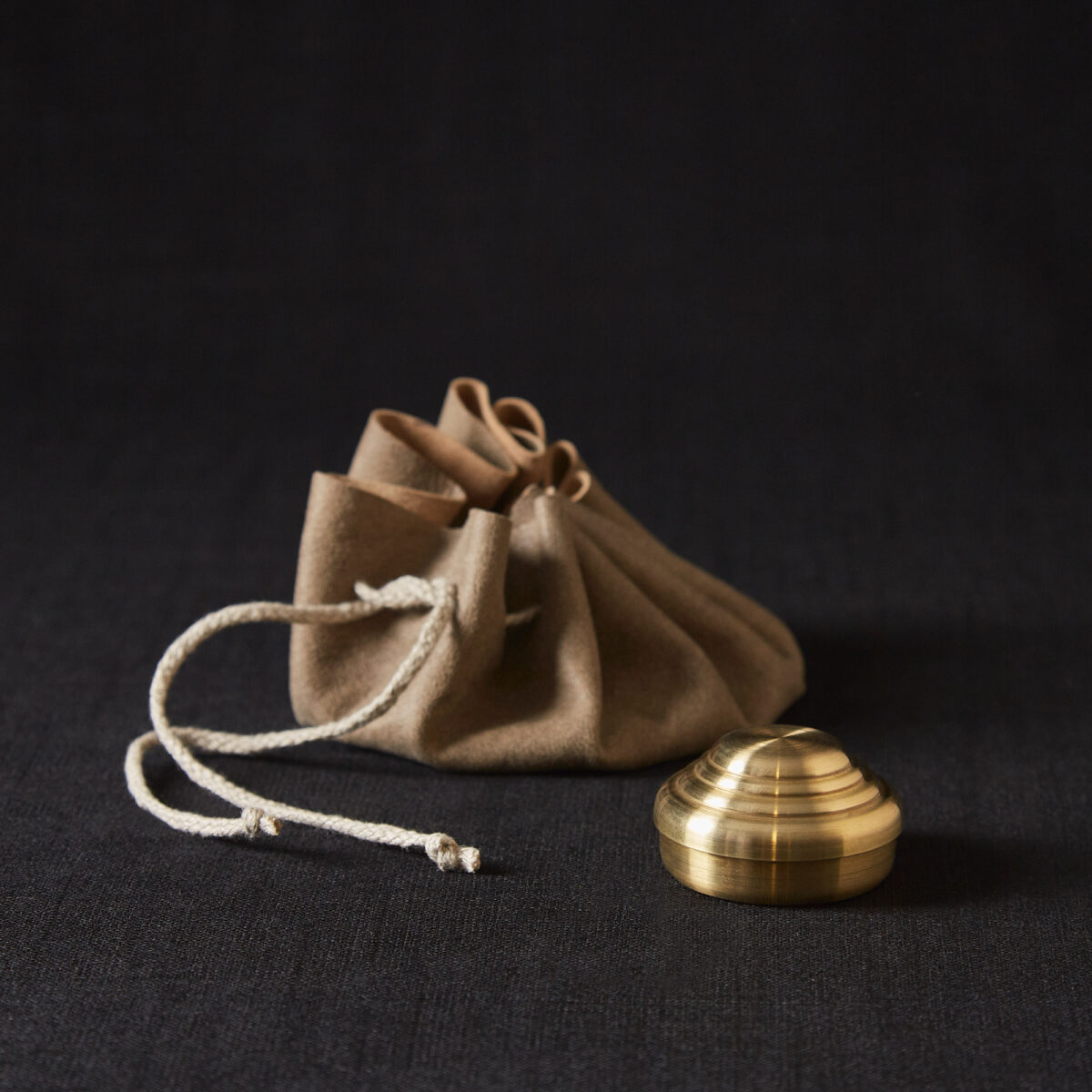Gewürzdose von Jens Sierra Lingemann im Hausgemachtes Online Shop erhältlich in Kombination mit einem Säckchen aus Wildleder, verschließbar mit einer Kordel. Die Dose glänzt metallisch und ist rund, mit Abstufungen im Deckel.